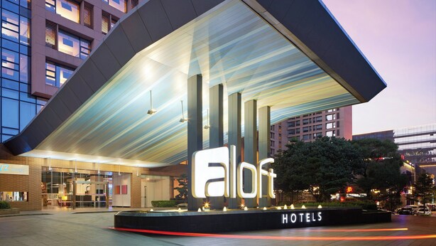 Das Außergewöhnliche Aloft Hotel mit modernem Design, inklusive einer großen beleuchteten Signage und einem überdachten Eingangsbereich.