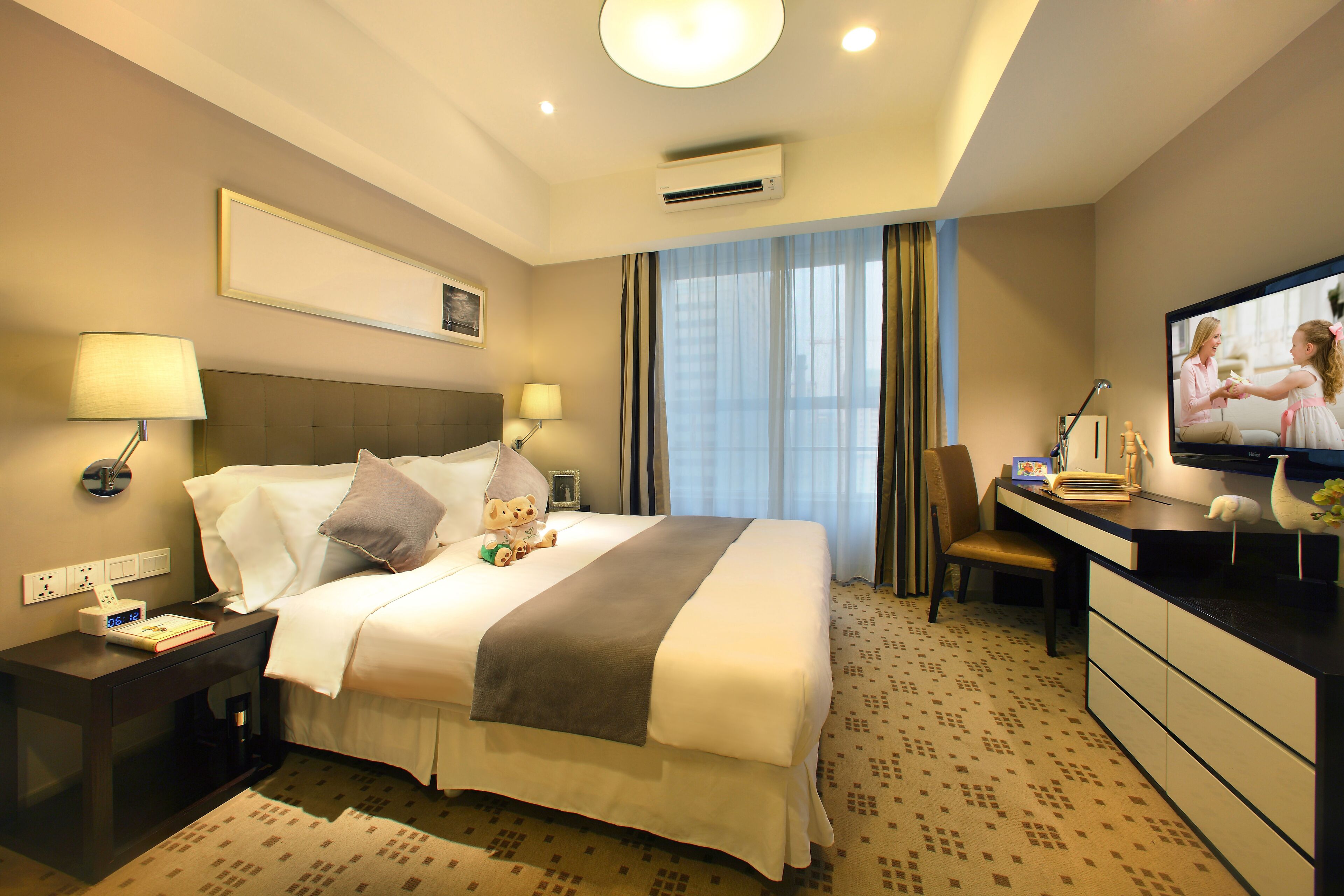 A hotel room with a bed, bedside tables, a desk, a chair, a television, and a window with curtains.