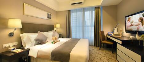 A hotel room with a bed, bedside tables, a desk, a chair, a television, and a window with curtains.