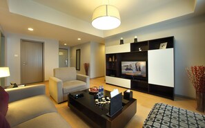 A modern living room with a sofa, a coffee table, a TV, and a bookshelf. - Somerset Heping Shenyang (Shenyang)