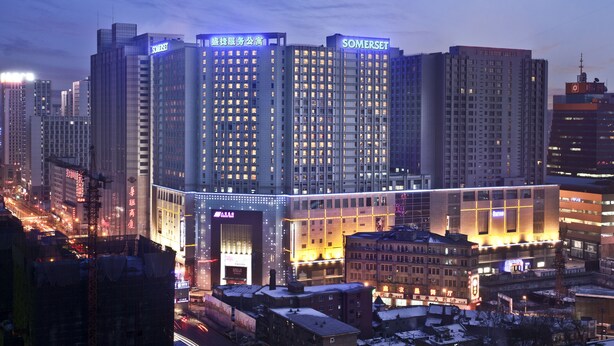 Un edificio de gran altura con múltiples pisos, ventanas amplias y señalización iluminada.