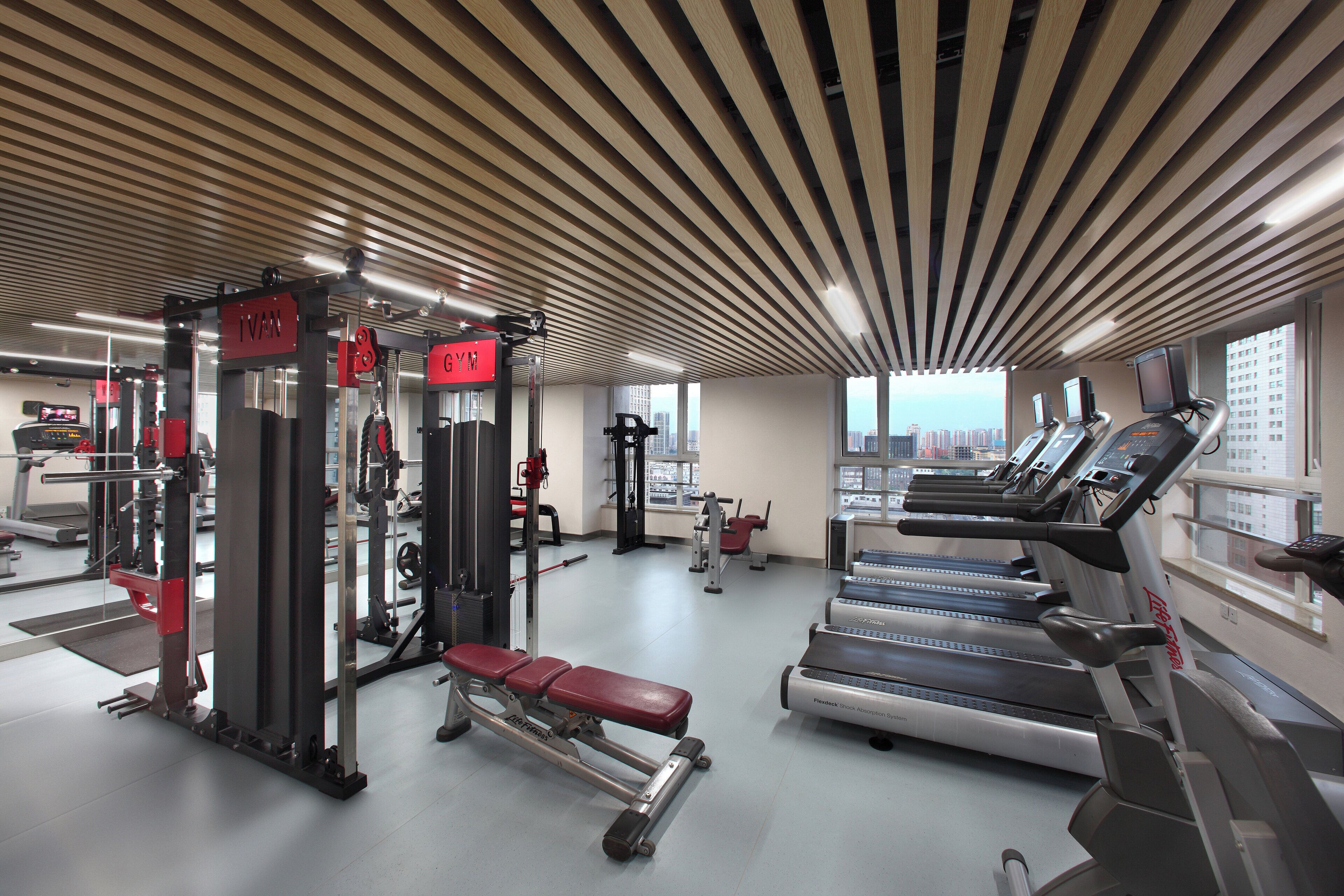 Une salle de sport équipée de tapis de course, d’appareils de musculation et de bancs.