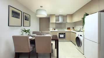 A modern kitchen with a dining area, including a table with chairs, a washing machine, and a hanging light fixture.