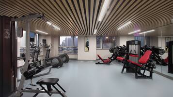 A gym with various exercise equipment, large windows, and a city view.