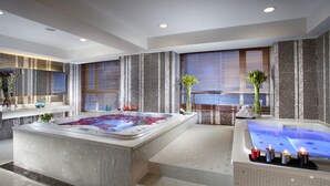 Un moderno espacio de spa con un amplio jacuzzi, una sala de vapor independiente y una zona de estar con velas.