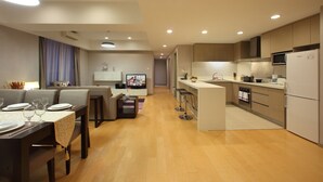 Una cocina moderna con una isla central, microondas empotrado y horno. Hay una zona de comedor con una mesa dispuesta para cuatro personas y un sofá.