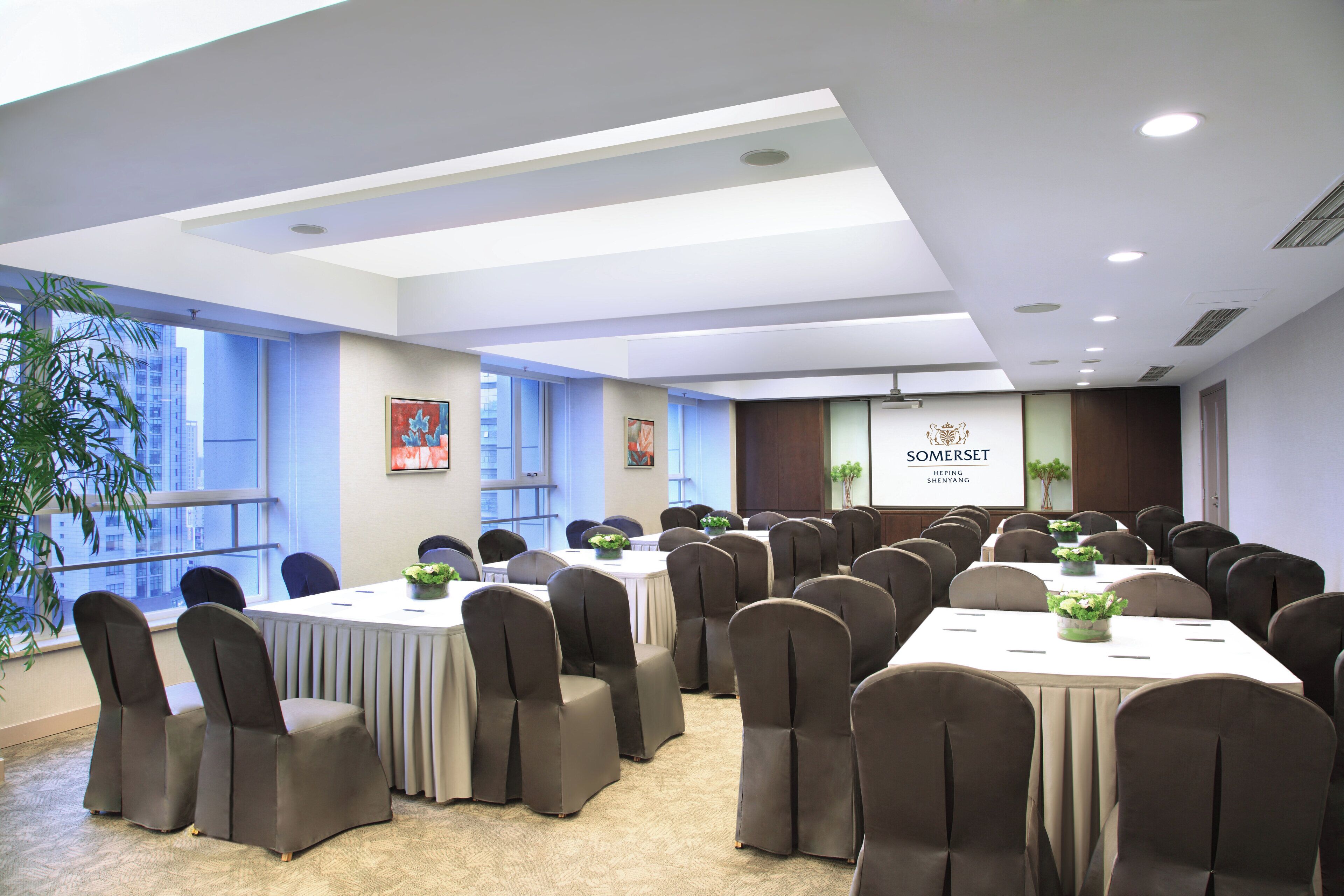A conference room with multiple tables and chairs, large windows, and a sign reading "SOMERSET".