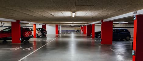 A multi-level parking garage with red pillars and a concrete ceiling.