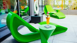 Un espacio exterior moderno con sillones reclinables verdes y una pequeña mesa con una bebida.