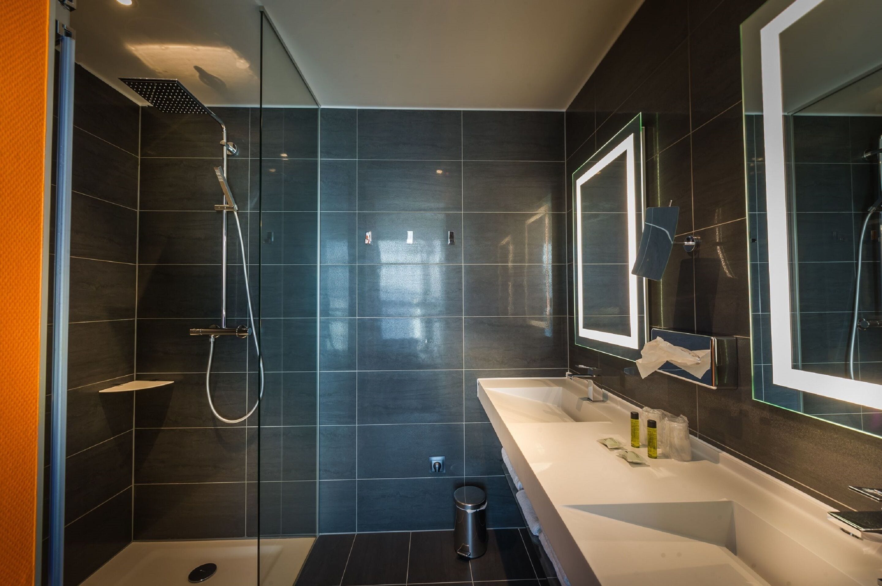 A modern bathroom with a glass-enclosed shower, a white sink, and a large mirror.