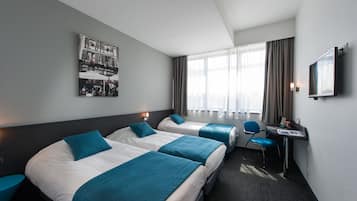 Una habitación de hotel con dos camas, un escritorio, una silla y un televisor.