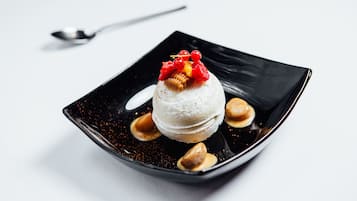 A dessert on a black plate with a spoon.