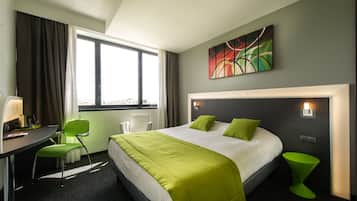 Habitación de hotel con una cama grande, un escritorio con silla, una ventana con cortinas y un cuadro en la pared.