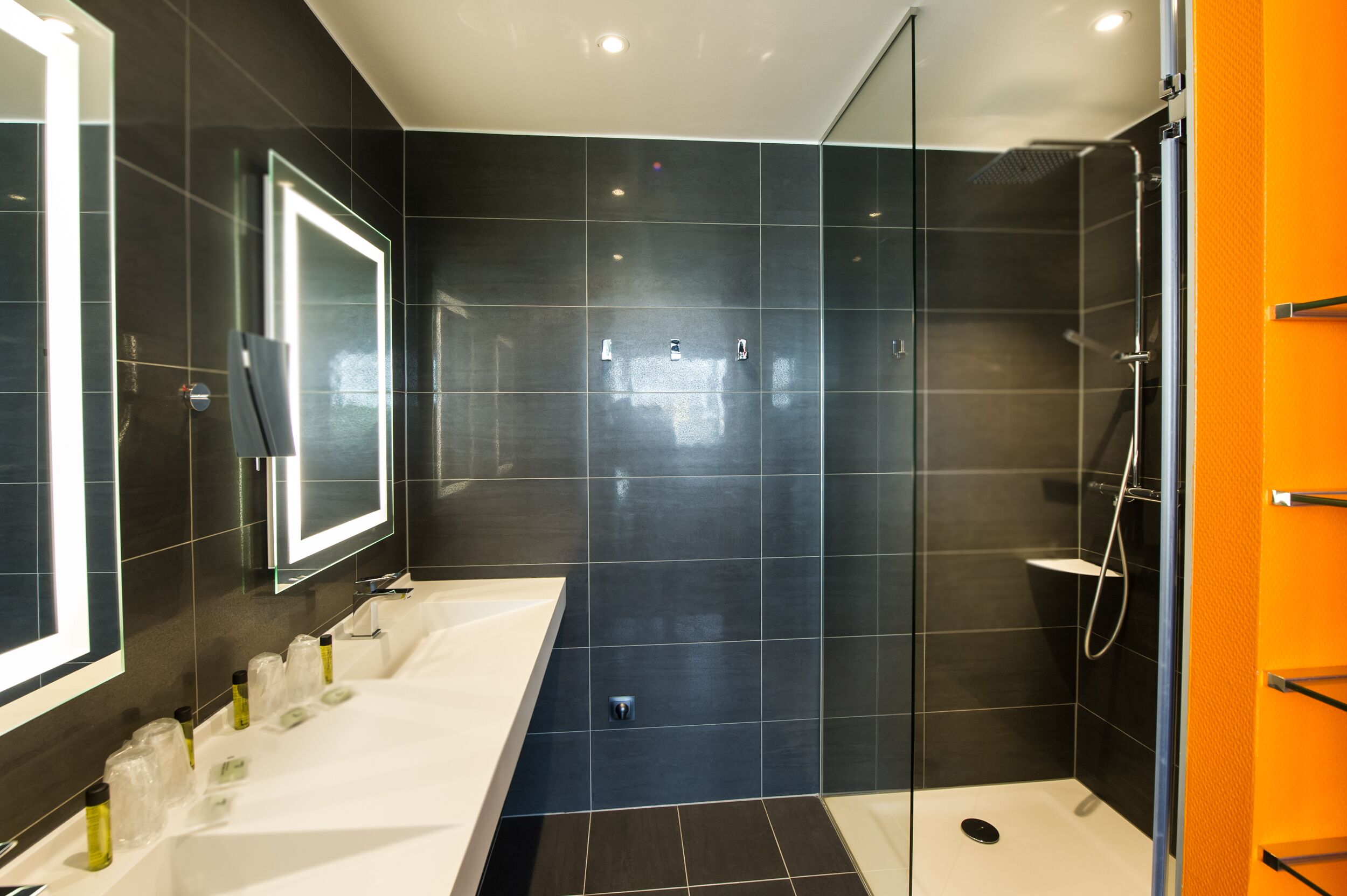 A modern bathroom with a large mirror, a bathtub, and a shower area.