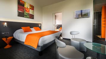 Moderni hotellihuone, jossa on suuri sänky, lasipöytä, tuoli ja peili.