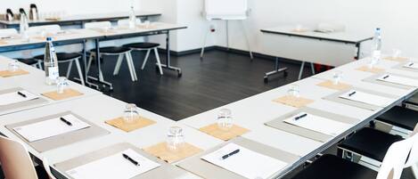 A conference room with long tables, chairs, and a whiteboard.