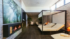 Zona de spa con chimenea, sillones reclinables y un gran mural en la pared.