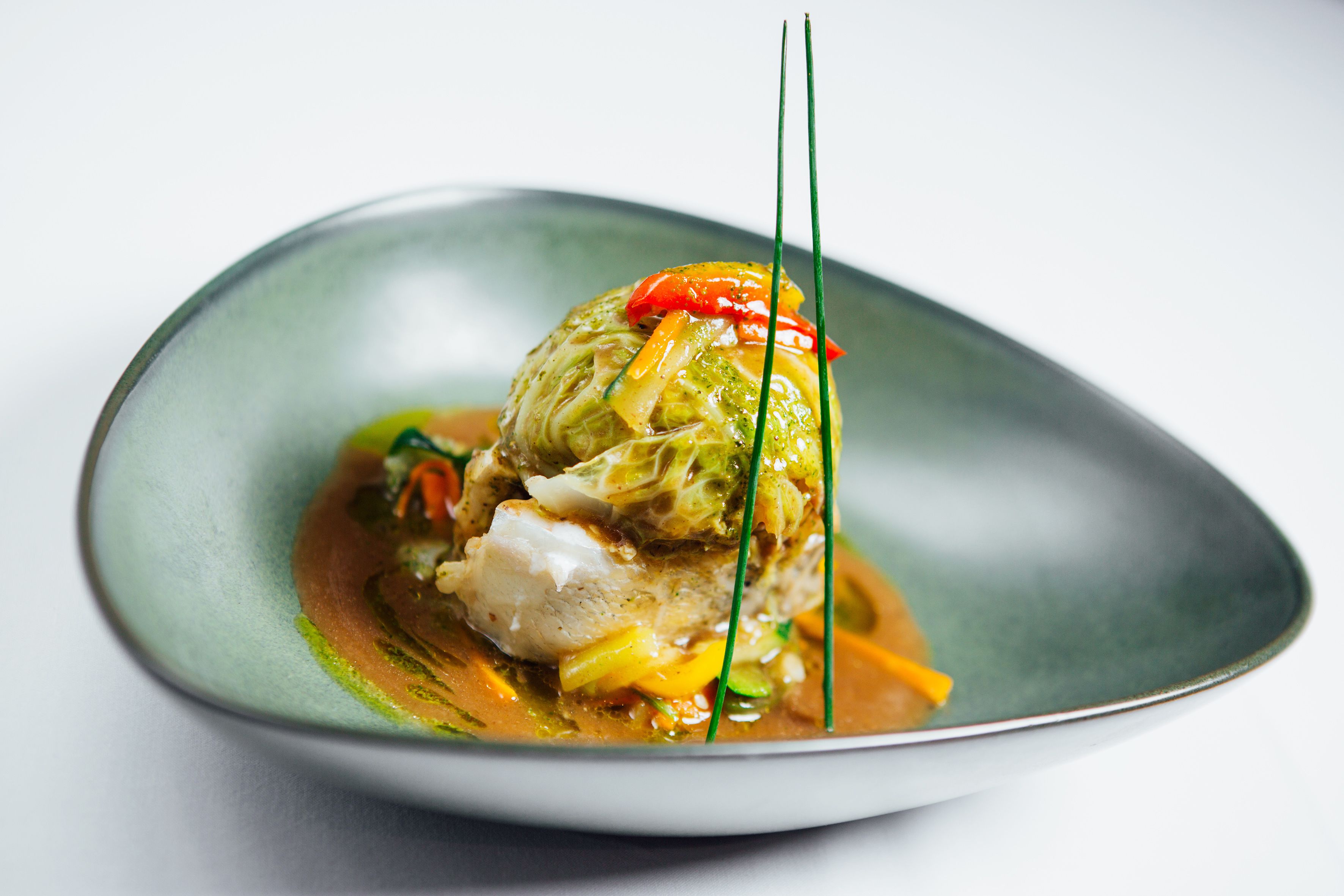 A dish with a green plate, a piece of meat, and vegetables.