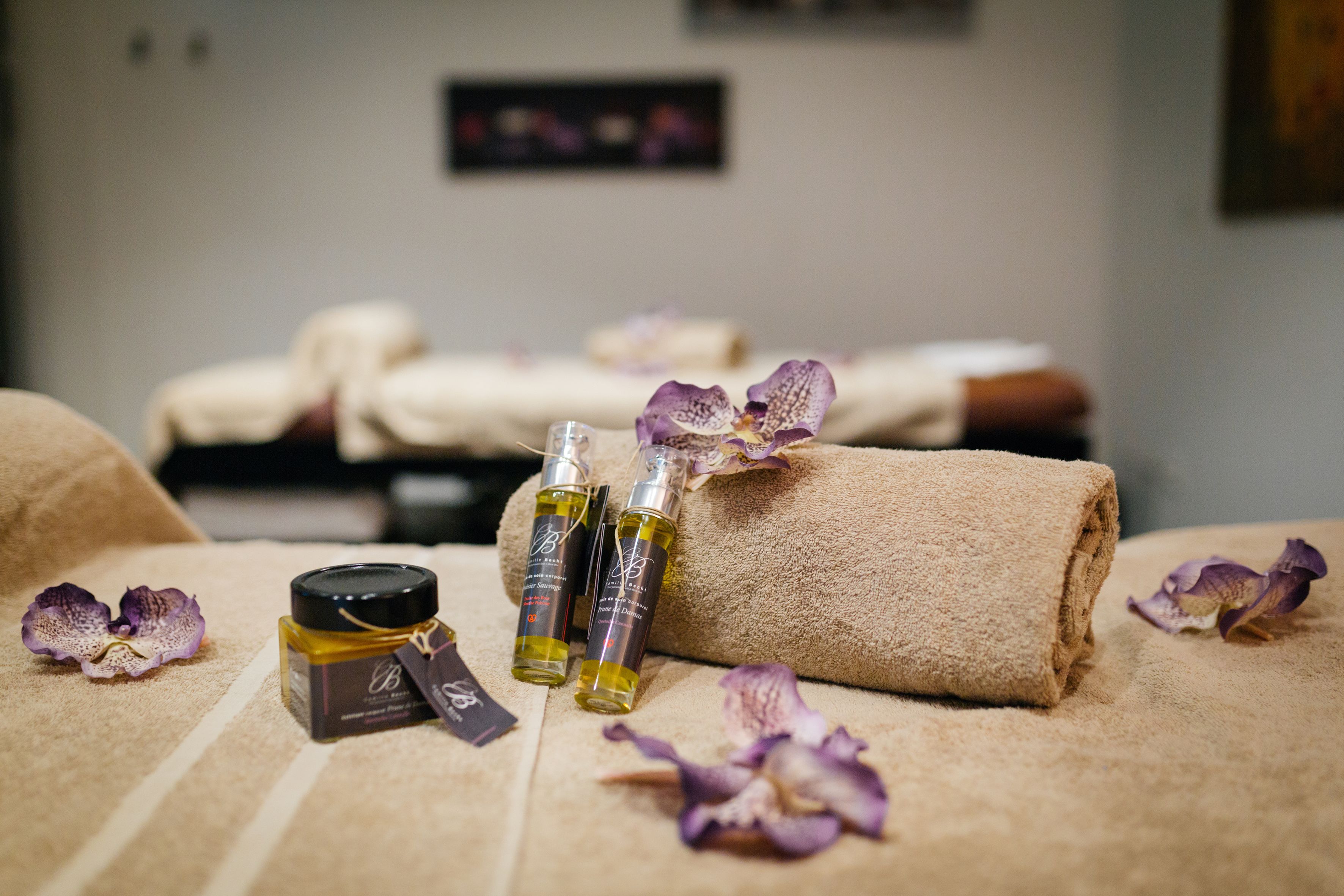 A spa setting with towels, bottles of oil, and orchid petals.