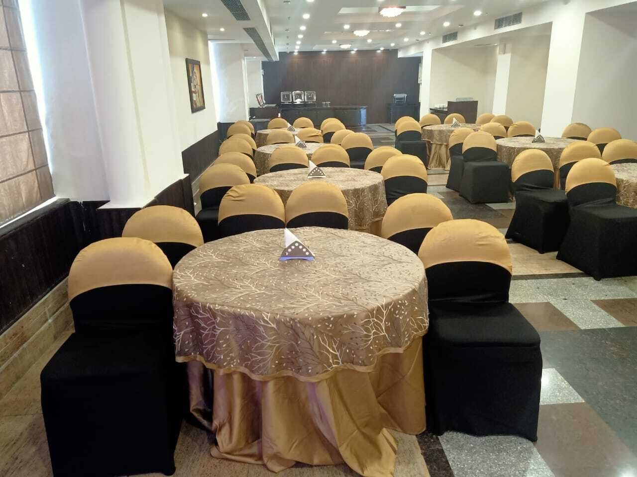 A conference room with round tables, black chairs, and yellow sashes.