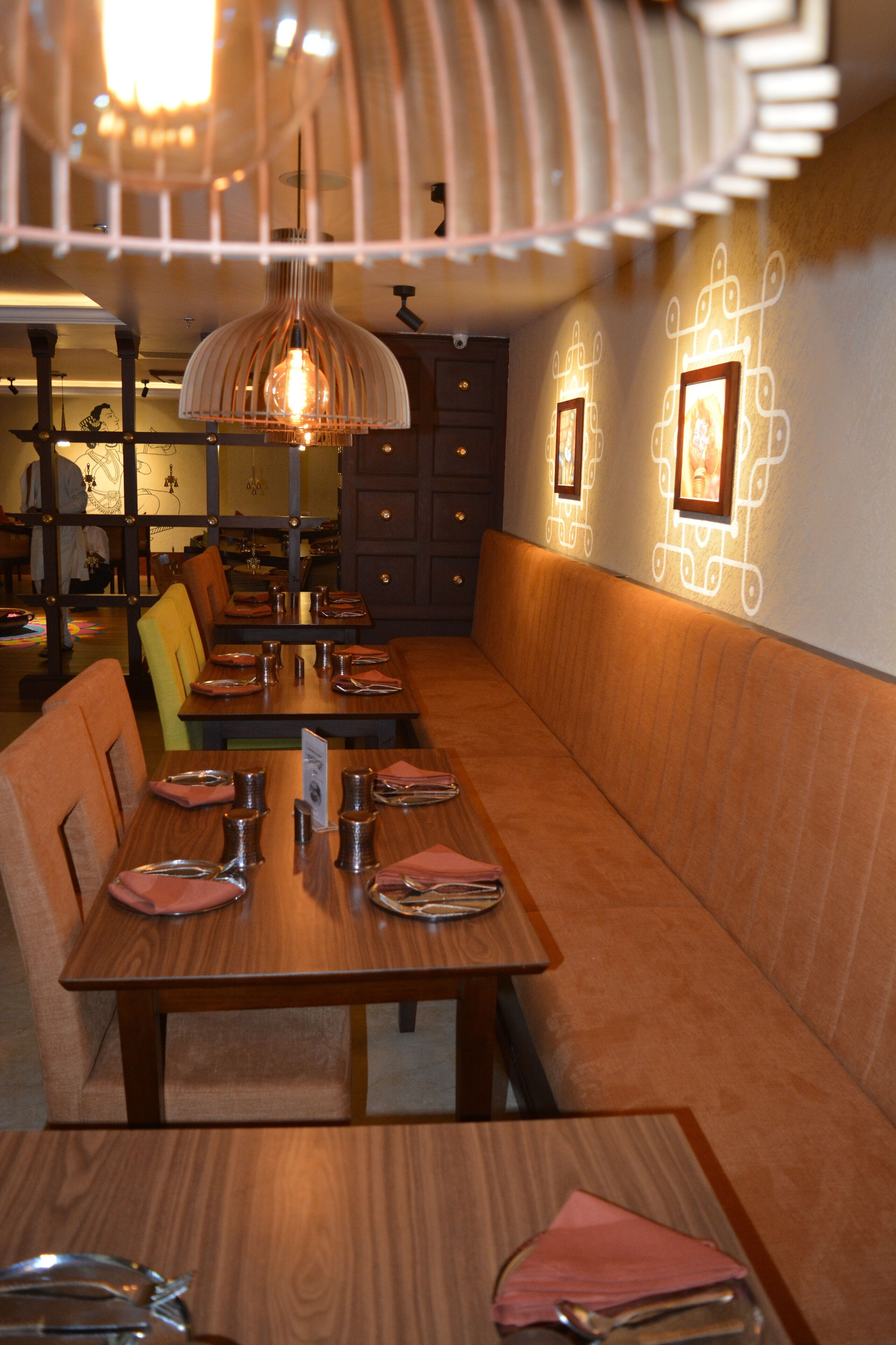 A restaurant with wooden tables and benches, pendant lighting, and wall-mounted picture frames.