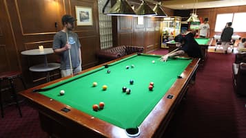 A pool table with balls, a billiard cue, and a person playing.