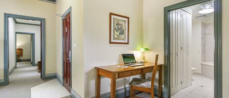 A hallway with a wooden desk, chair, and a framed picture on the wall.
