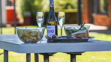 Uma mesa com uma garrafa de vinho VIVO, duas taças, um prato de batatas fritas e um sanduíche.