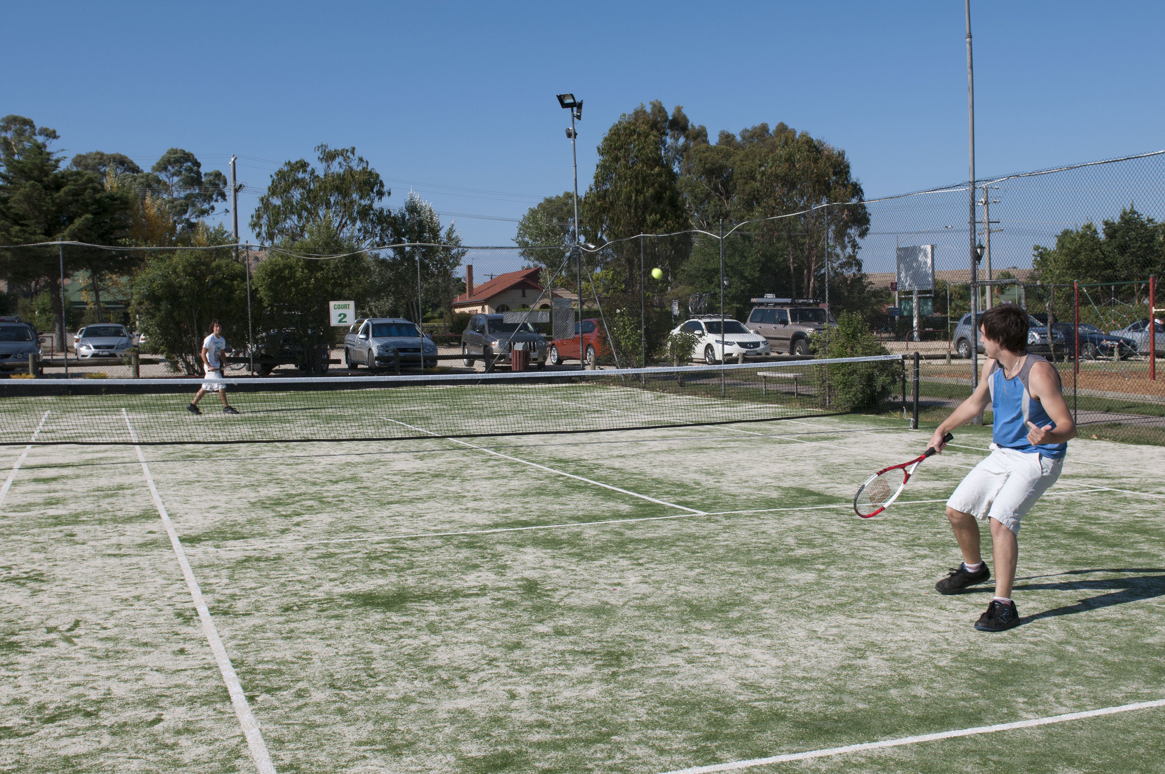 A tennis court with a net in the middle, surrounded by a fence.