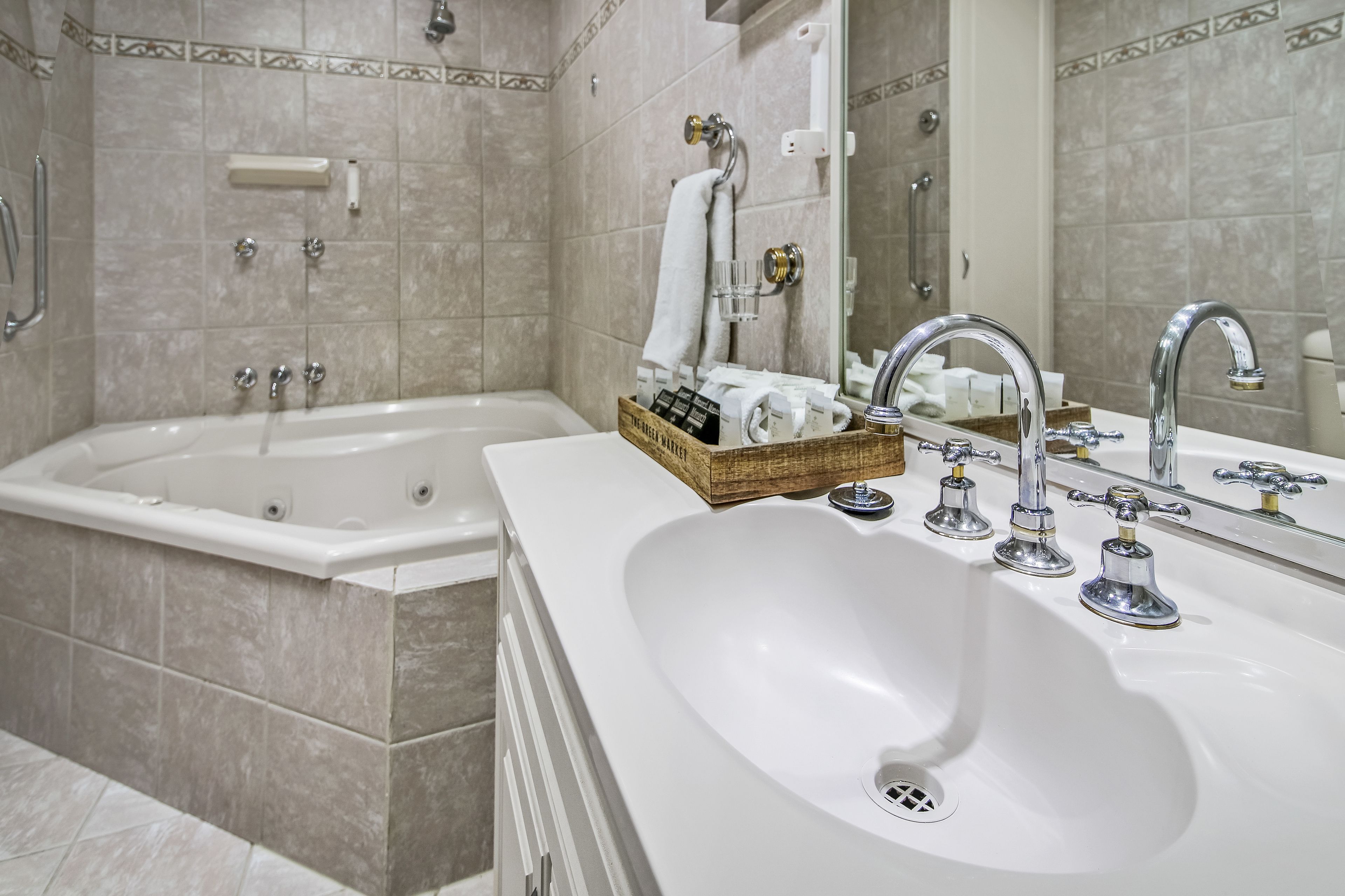 Un baño moderno con una bañera, un lavabo de dos grifos y un espejo.