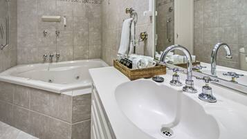 A modern bathroom with a bathtub, a sink with two faucets, and a mirror.