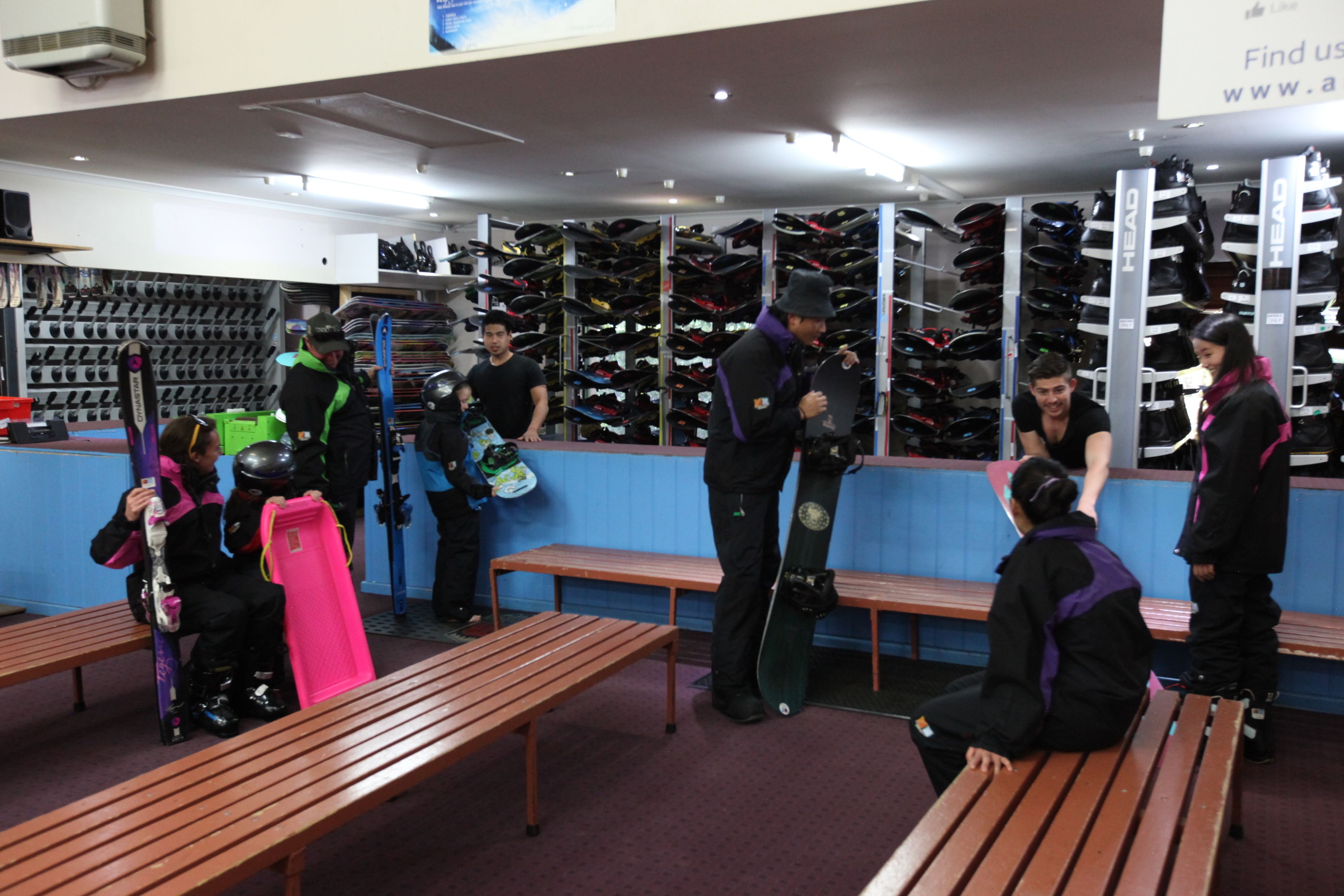 A shoe store with multiple shelves of shoes and benches for customers.