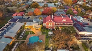 Vue aérienne d’un quartier résidentiel avec des maisons, des panneaux solaires et une piscine.