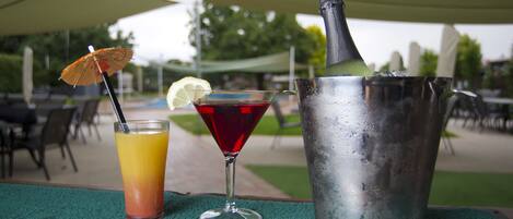 A table with a cocktail, a bottle, and a glass with a straw.
