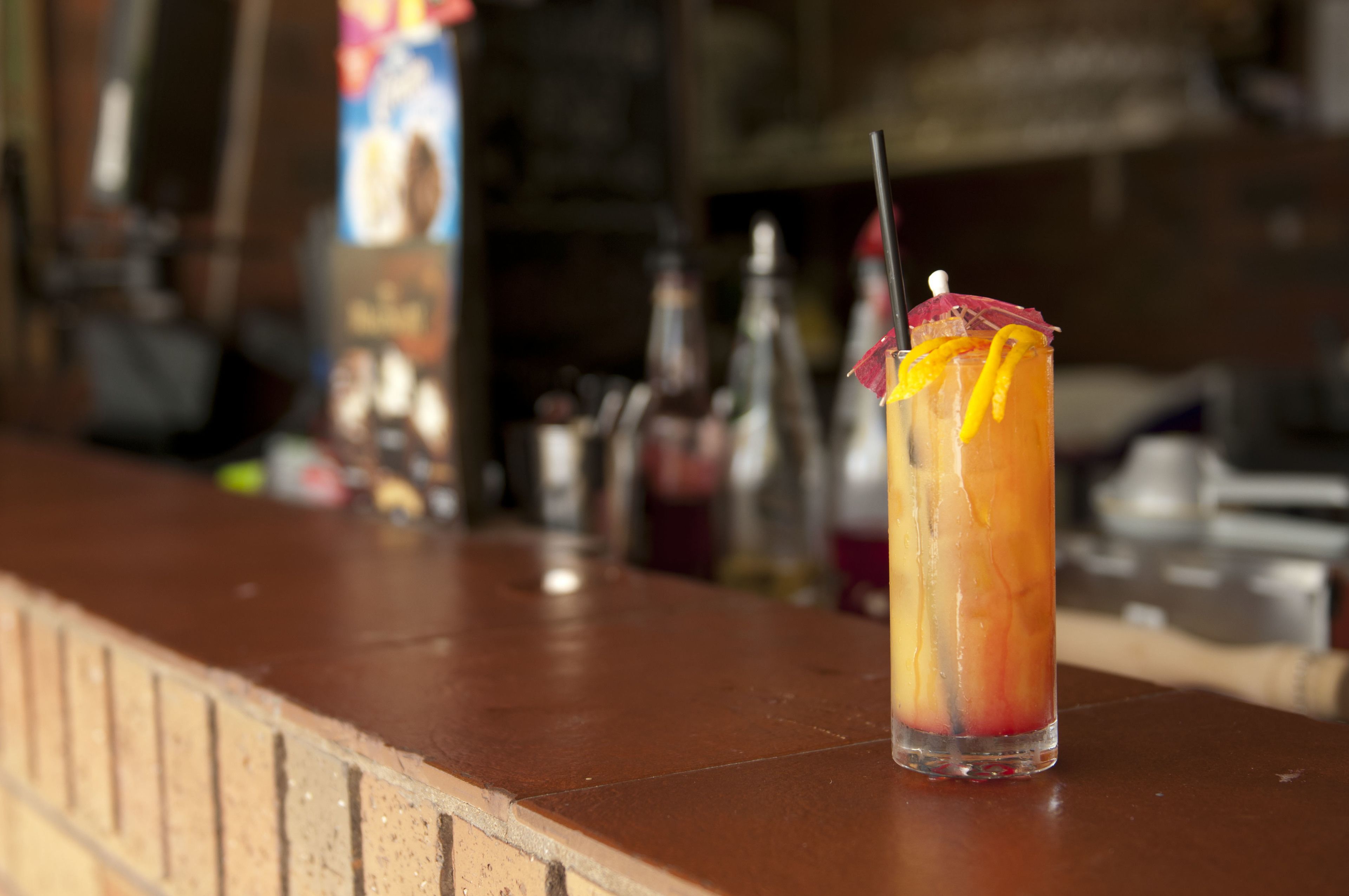 A tall glass with a straw and a garnish on a bar counter.