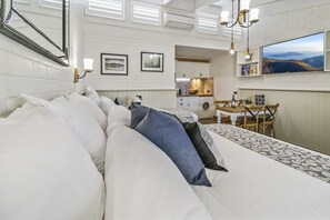 A bedroom with a large bed, a dining area with a table and chairs, a kitchen, and a TV mounted on the wall. - Alzburg Resort (Mansfield)
