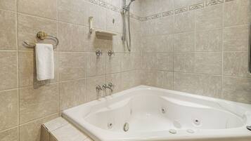 A bathroom with a bathtub, a towel rack, a showerhead, and a soap dish.