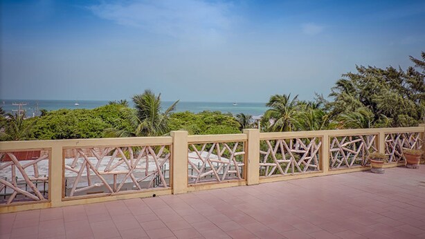 Een balkon met uitzicht op zee, een houten balustrade en bloempotten.