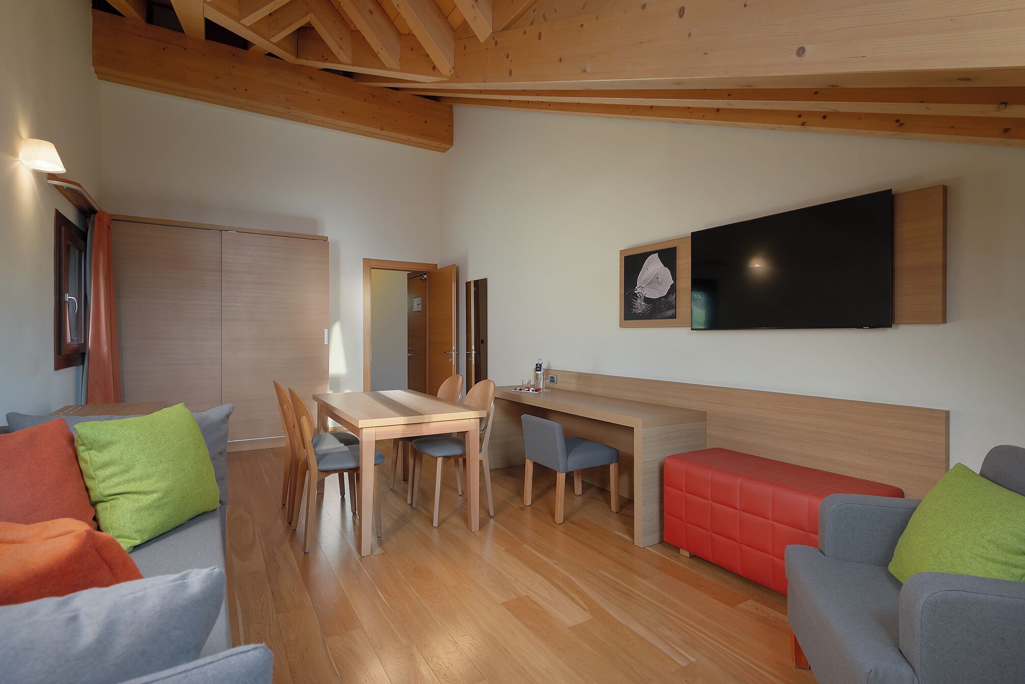 Un intérieur moderne avec une table à manger en bois, des chaises, un canapé et un téléviseur à écran plat fixé au mur.