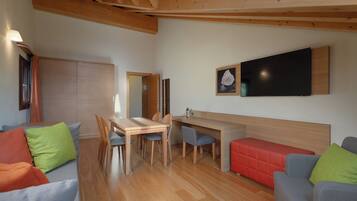 Un intérieur moderne avec une table à manger en bois, des chaises, un canapé et un téléviseur à écran plat fixé au mur.