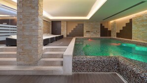 Uma área de piscina interna moderna, com paredes de pedra e água cristalina.