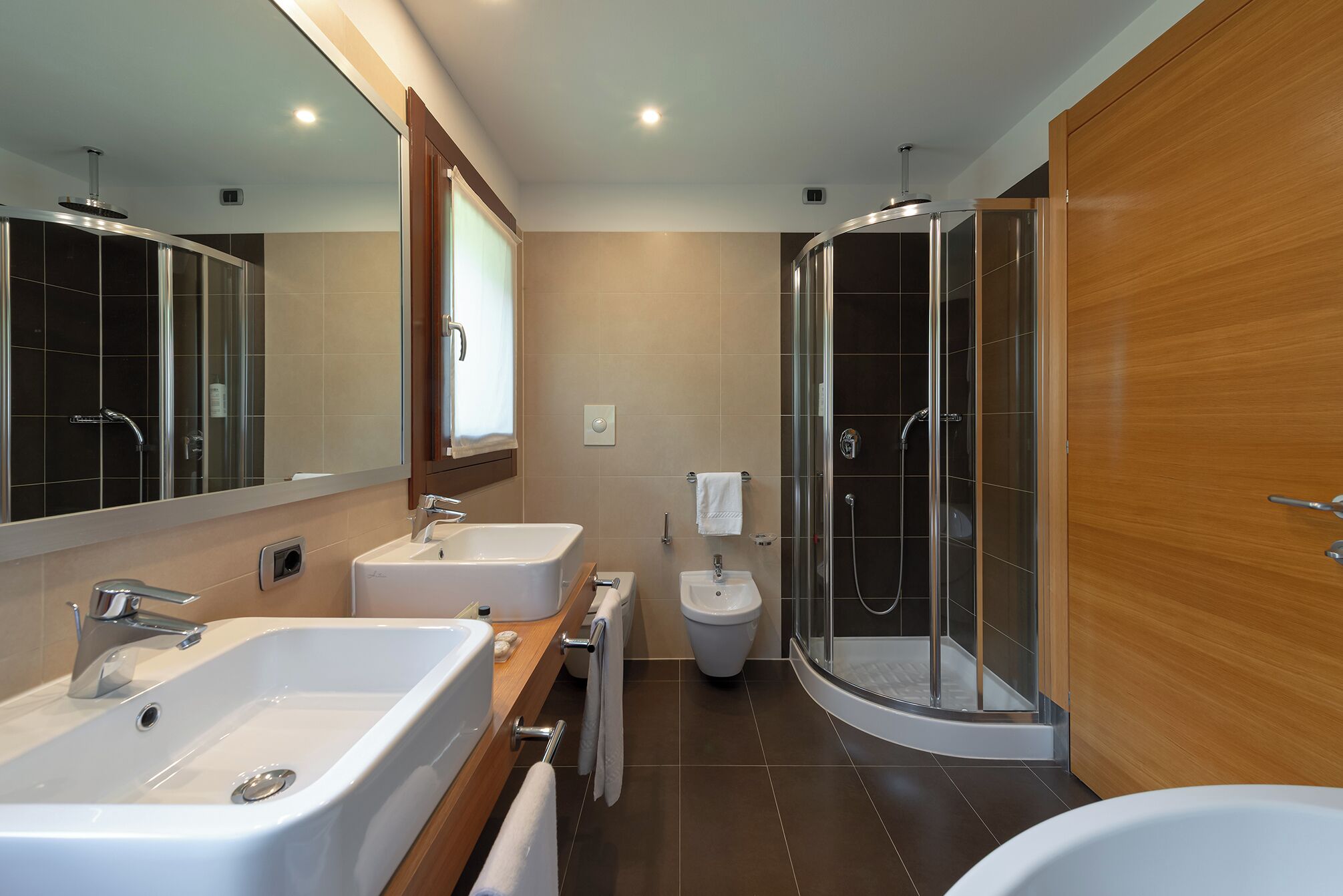 Un bagno moderno con due lavandini, una doccia e un water.