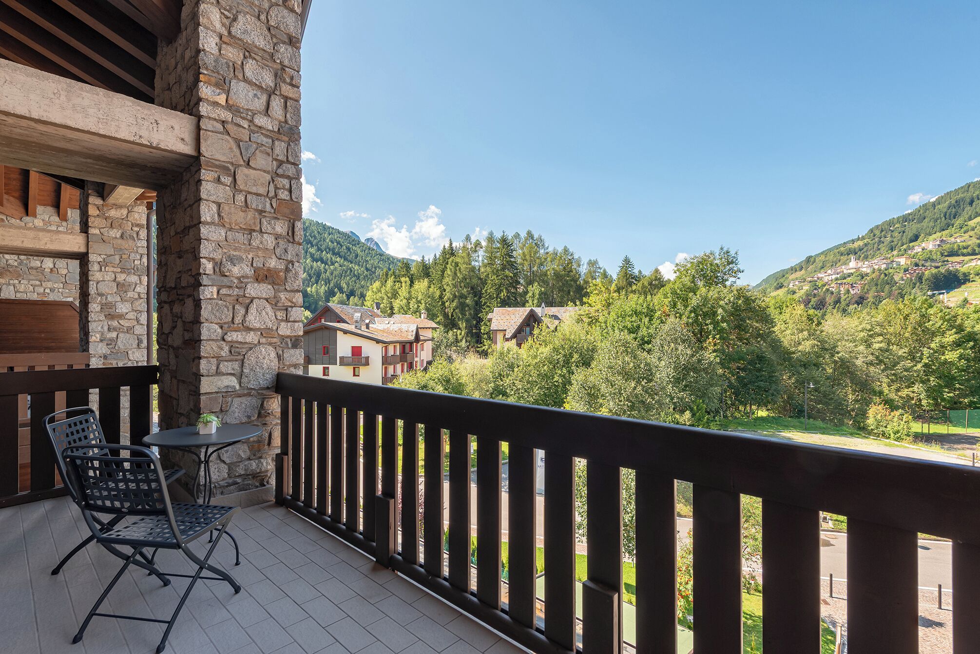 A balcony with a stone wall, a table, and two chairs.