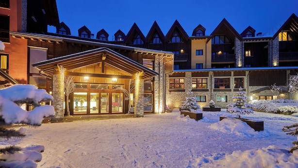 Um hotel com entrada coberta de neve e fachada de pedra.