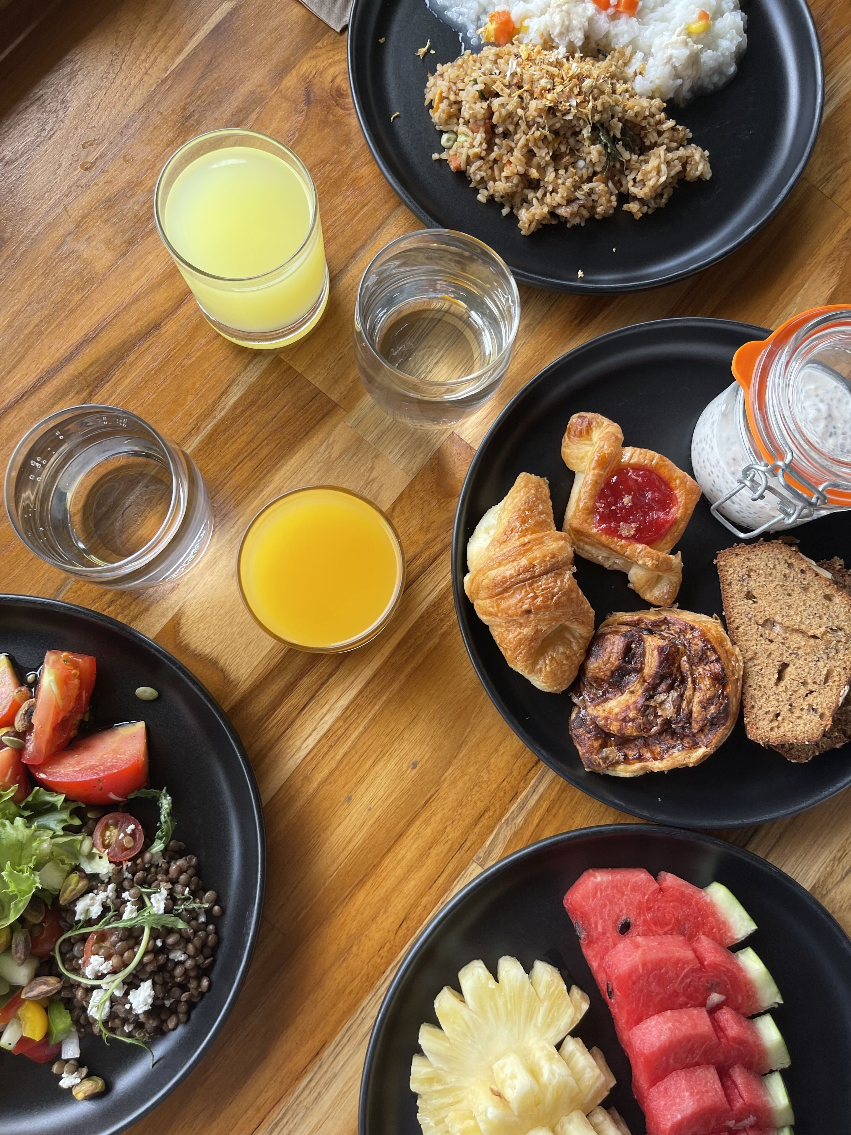 A breakfast setting with plates of food, glasses of orange juice, and a variety of pastries.