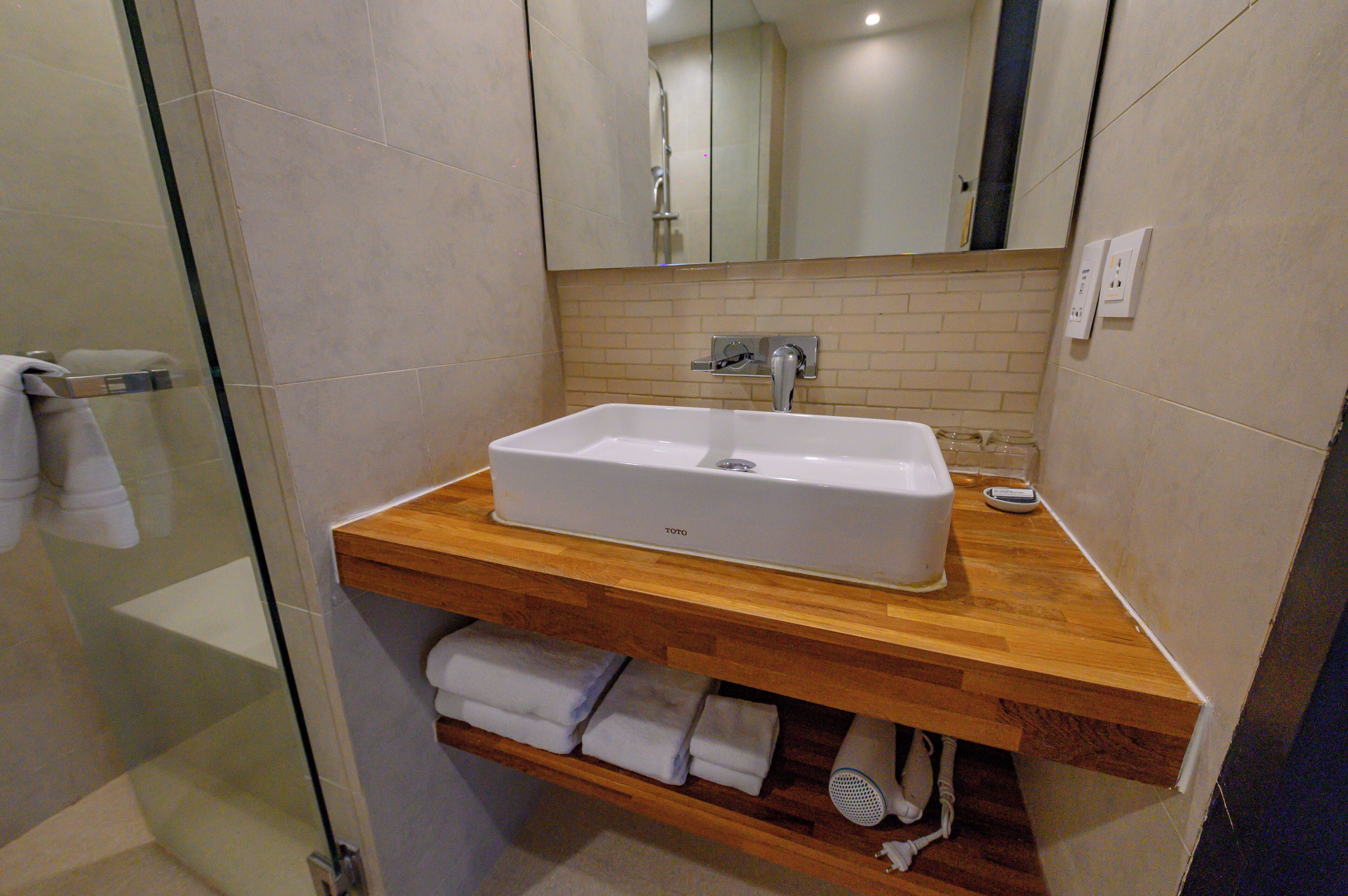 A bathroom with a white sink, wooden countertop, and a glass shower enclosure.