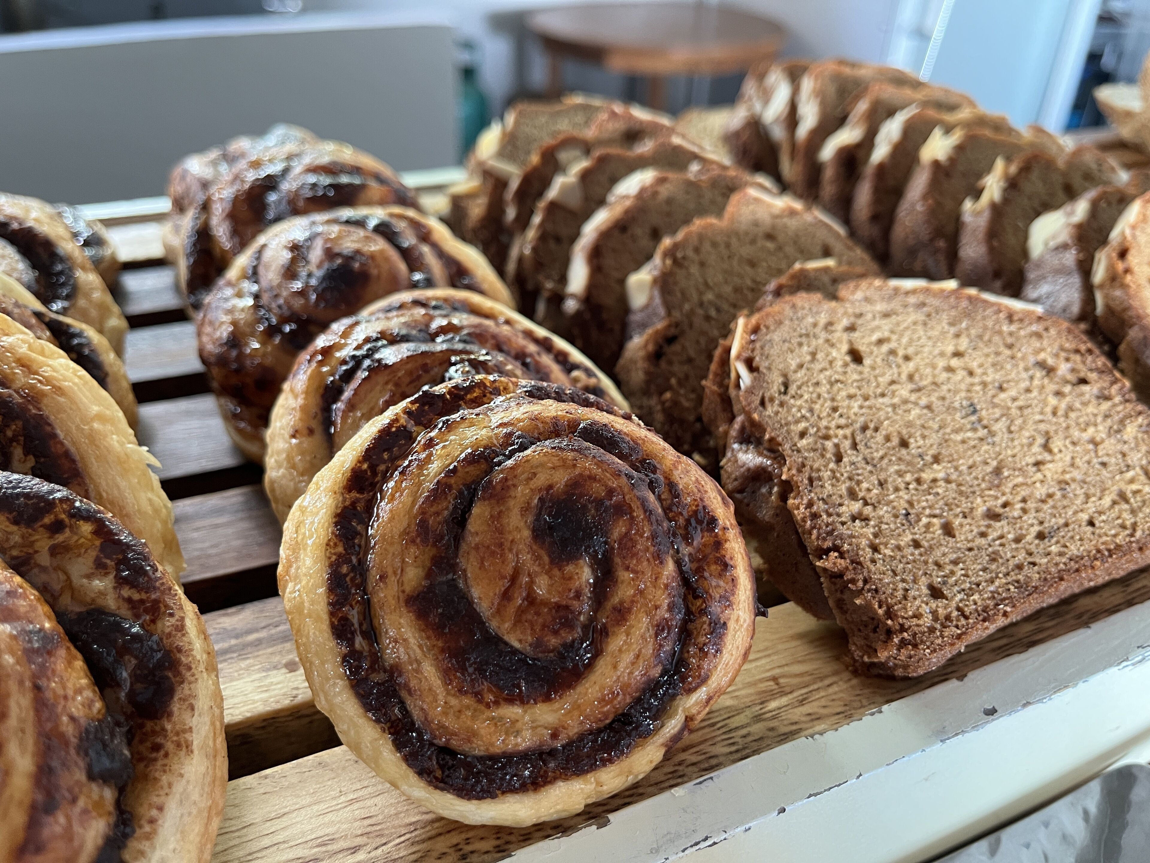 Verschillende soorten brood, waaronder een spiralenbroodje en plakken brood, gepresenteerd op een houten ondergrond.