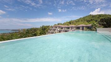 Una piscina al aire libre, sombrillas, sillones reclinables de piscina