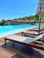 Una piscina al aire libre, sombrillas, tumbonas