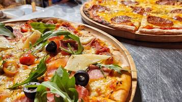 Zwei Pizzen mit unterschiedlichen Belägen auf einem Holzboden.